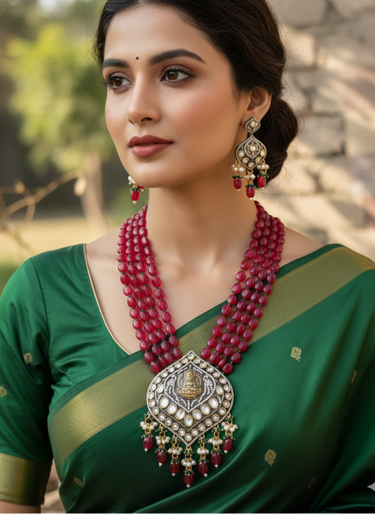 Woman wearing a green saree with red jewelry in an outdoor setting