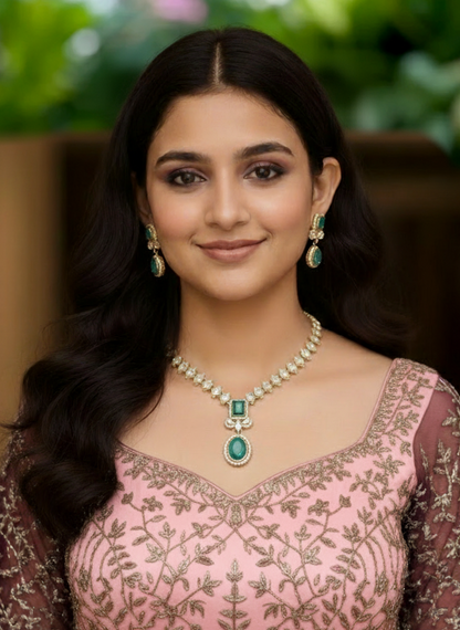 Woman wearing a pink embroidered dress with green jewelry against a blurred natural background